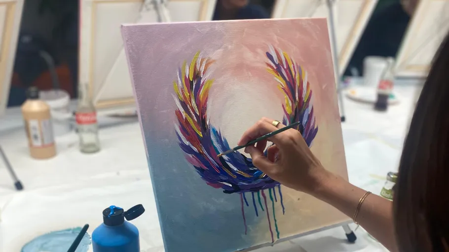 Person painting colorful feathers on canvas.