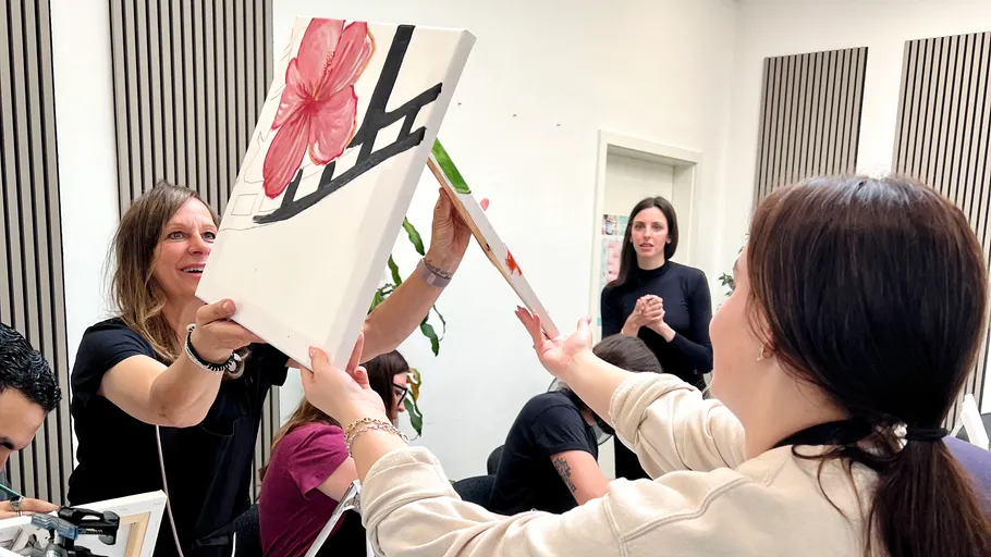 Women exchanging paintings in an art class.