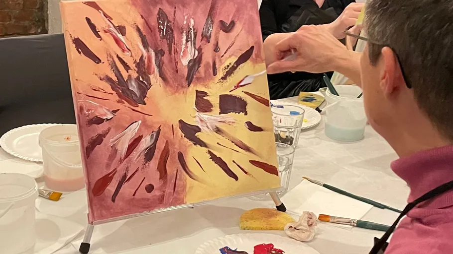 Person painting abstract art in a classroom.
