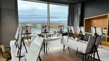 Leeres Kunststudio mit Staffeleien und Stadtblick.