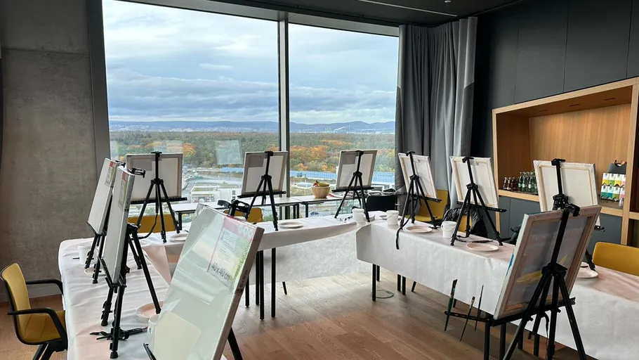Leeres Kunststudio mit Staffeleien und Stadtblick.