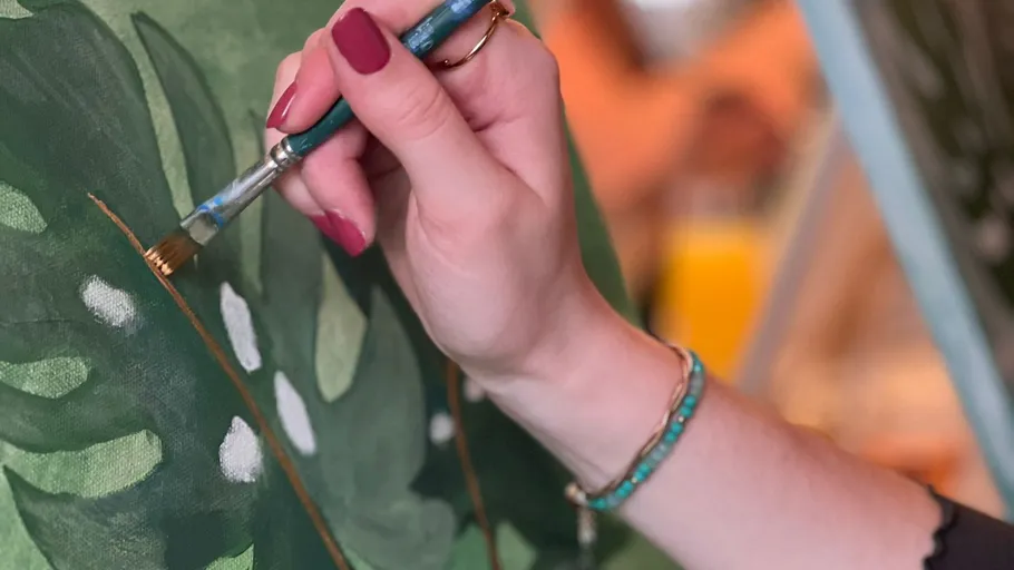 Hand painting green leaves on canvas.