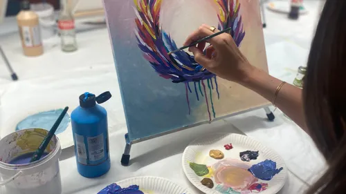 Person painting colorful design on canvas