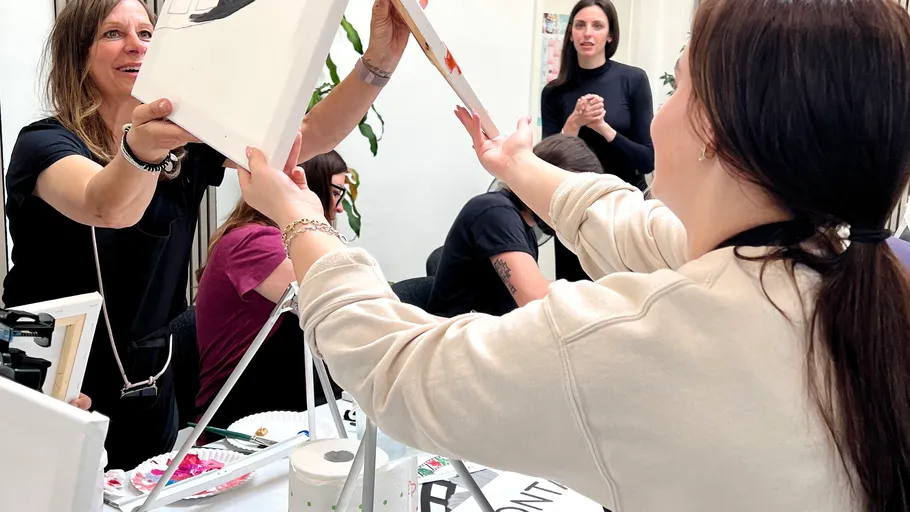 Two women exchanging a painting at a workshop.