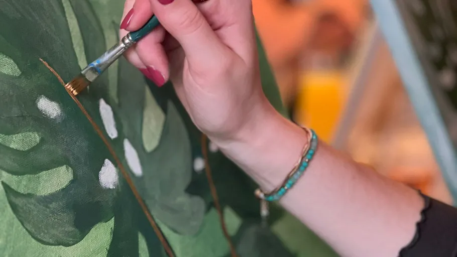 Hand painting green leaves on canvas.