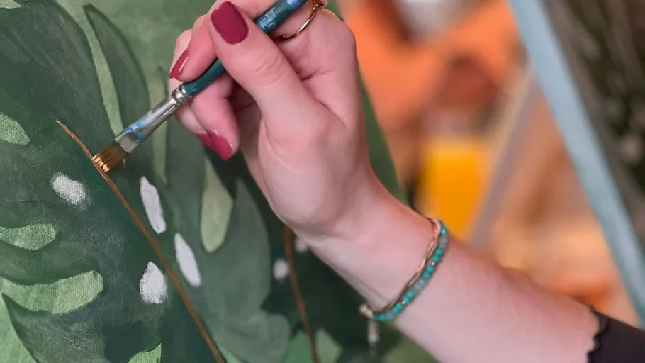 Hand painting green leaves on canvas.