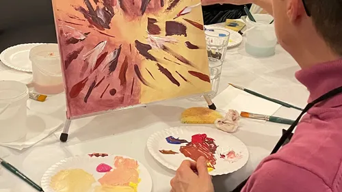 Person painting abstract art on canvas indoors.