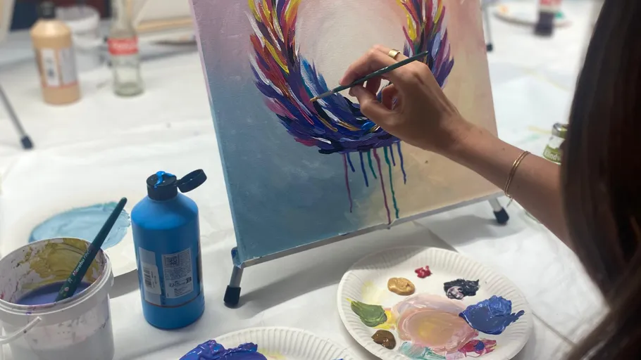 Person painting colorful circle on canvas indoors.