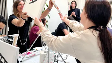 Women exchanging paintings in an art class.