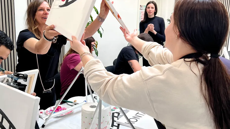 Women exchanging paintings in an art class.