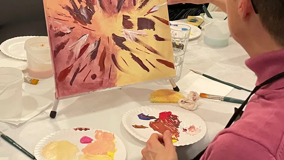 Person painting abstract art at a table.