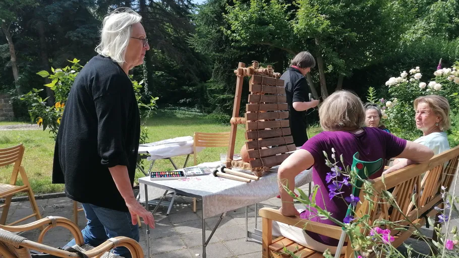 People sitting outdoors at a table, playing xylophone.