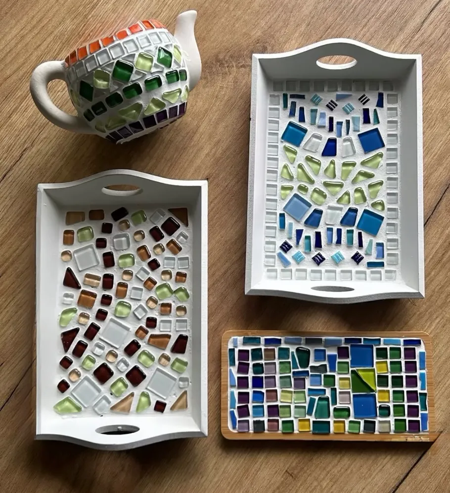 Mosaiktabletts und Teekanne auf Holzoberfläche.