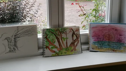 Drei Zeichnungen auf einer Fensterbank.