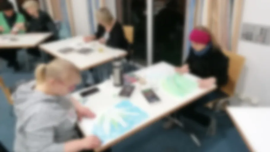 People drawing at tables in a classroom.