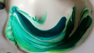 Gewirbelte grüne und blaue Farbe in einer Schale.
