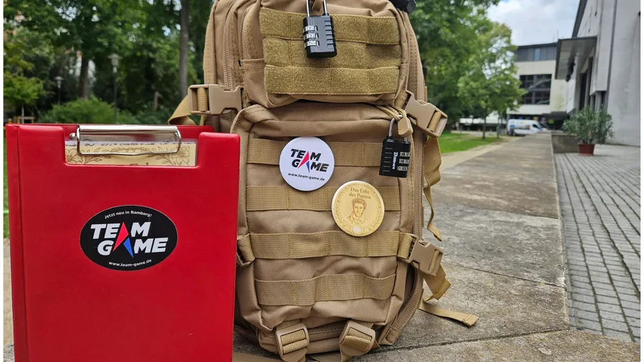 Rucksack und rote Box mit Schlössern draußen.