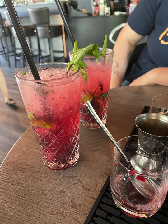 Two pink drinks with mint on wooden table.