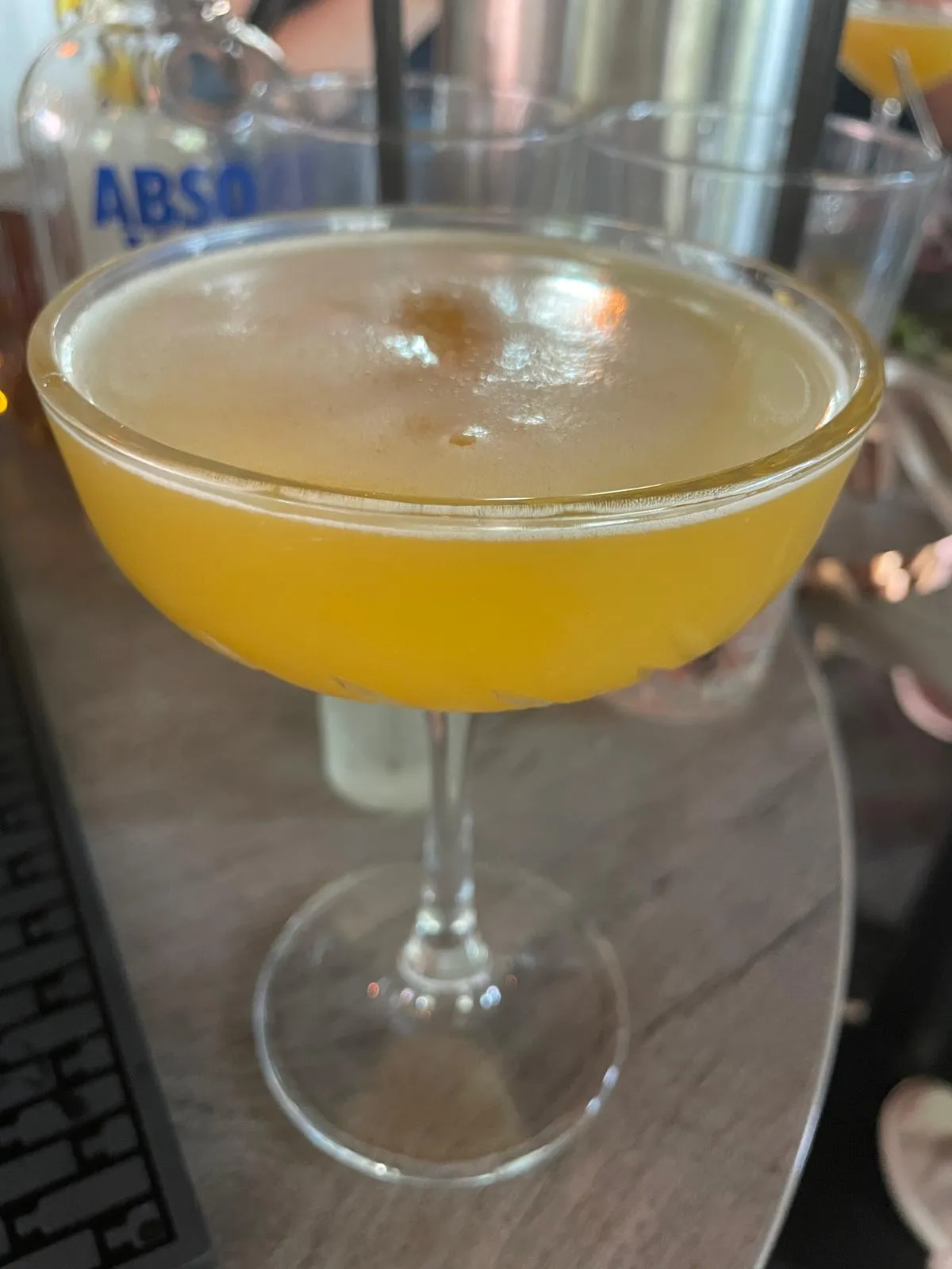 Gelber Cocktail in einem Glas auf Tisch.