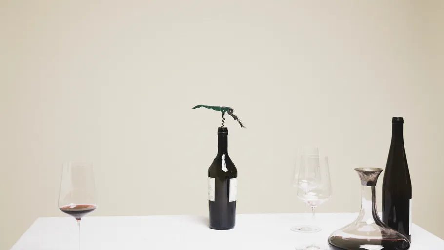 Wine bottles and glasses on white table.