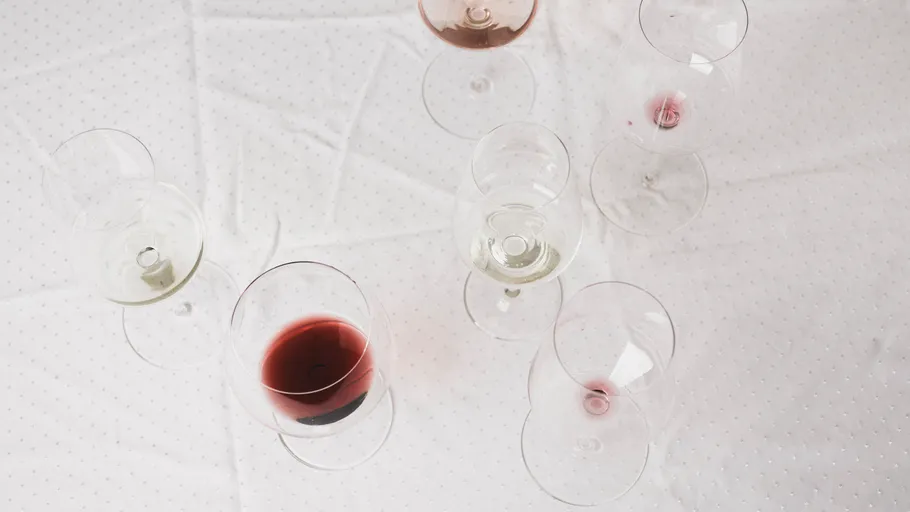Six wine glasses on a white tablecloth.