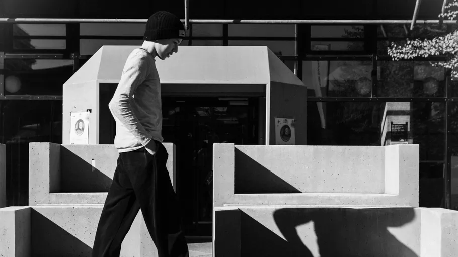 Man walks past concrete benches outside a building.