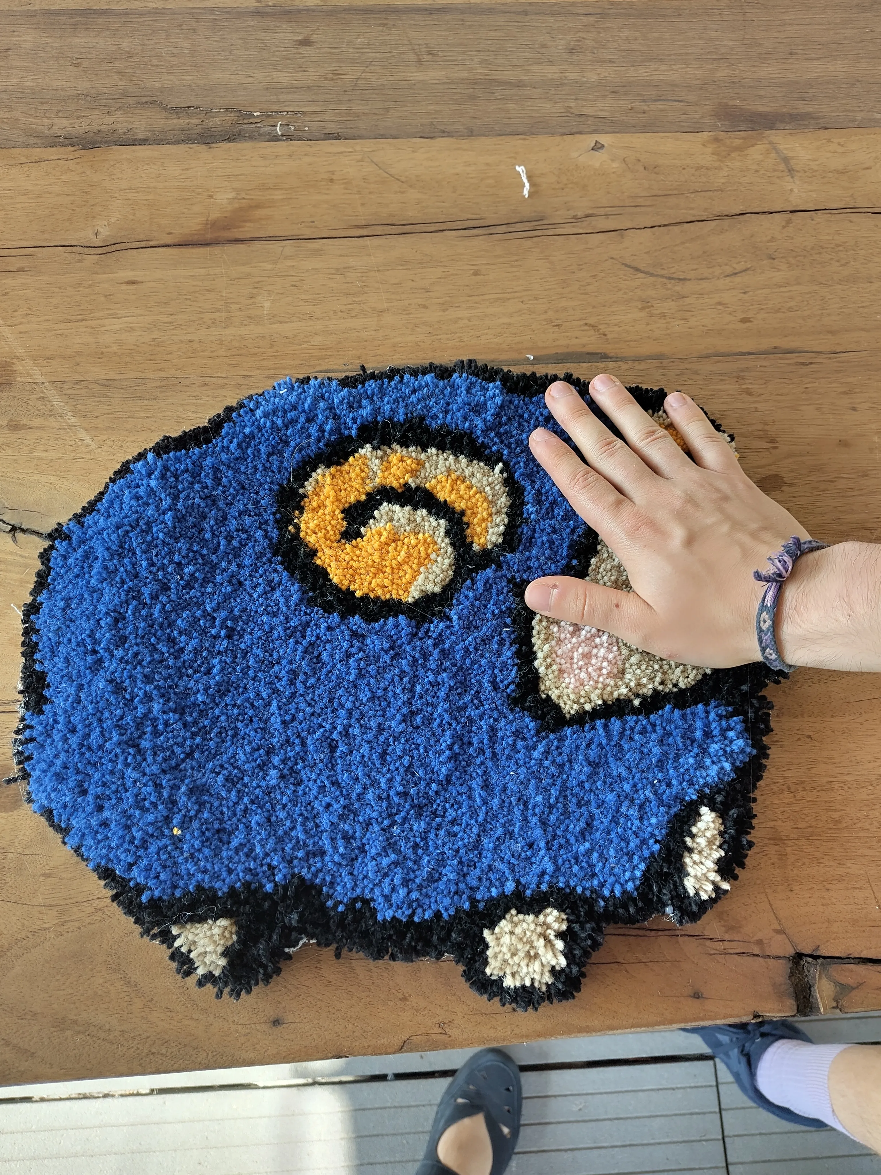 Hand berührt kleinen blauen Autoteppich auf Tisch.