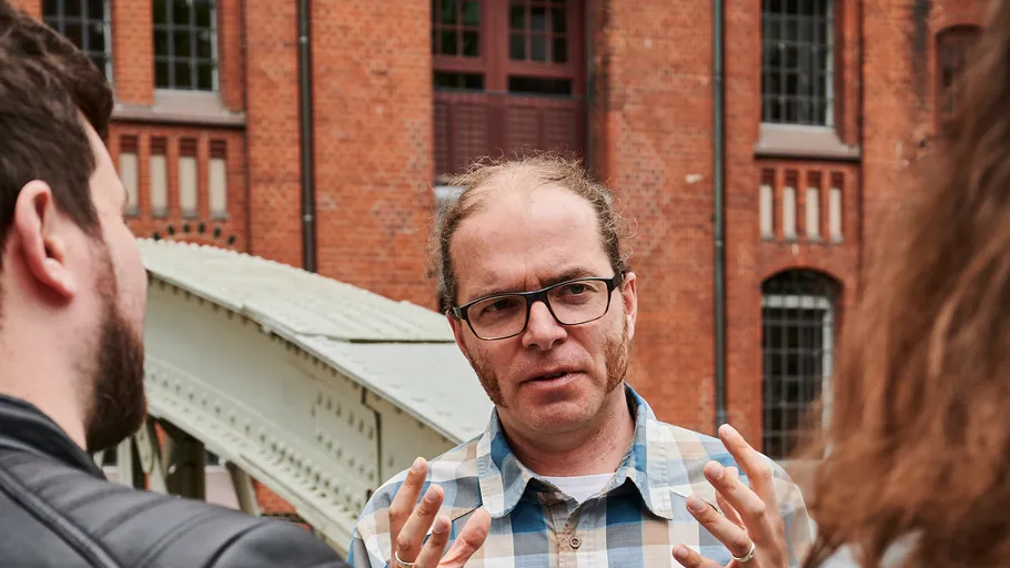 Man gesturing while talking in front of building.