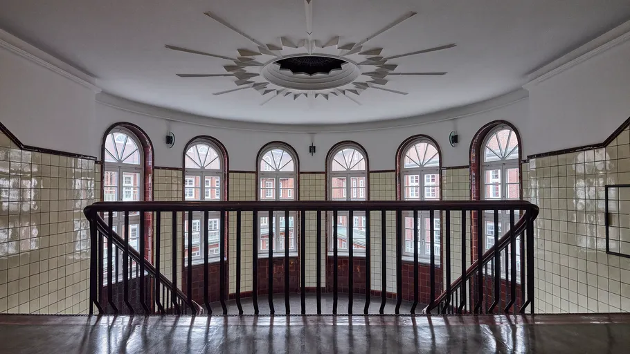 Gekrümmtes Treppenhaus mit großen Bogenfenstern.