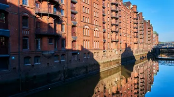 Brick buildings reflecting in a canal.