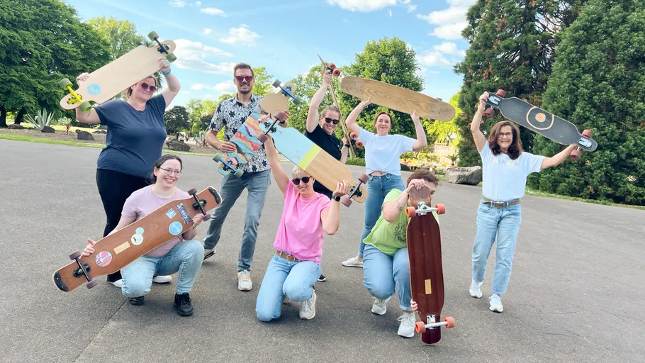 Group holding skateboards in a park.