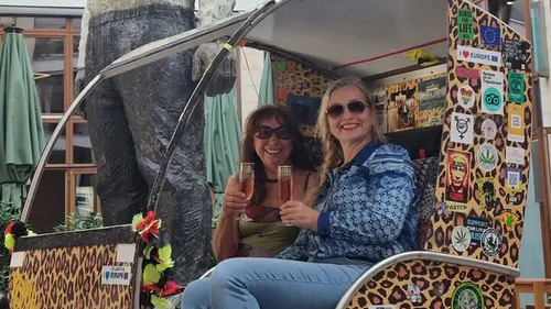 Zwei Frauen lächeln, in dekorierter Rikscha sitzend.