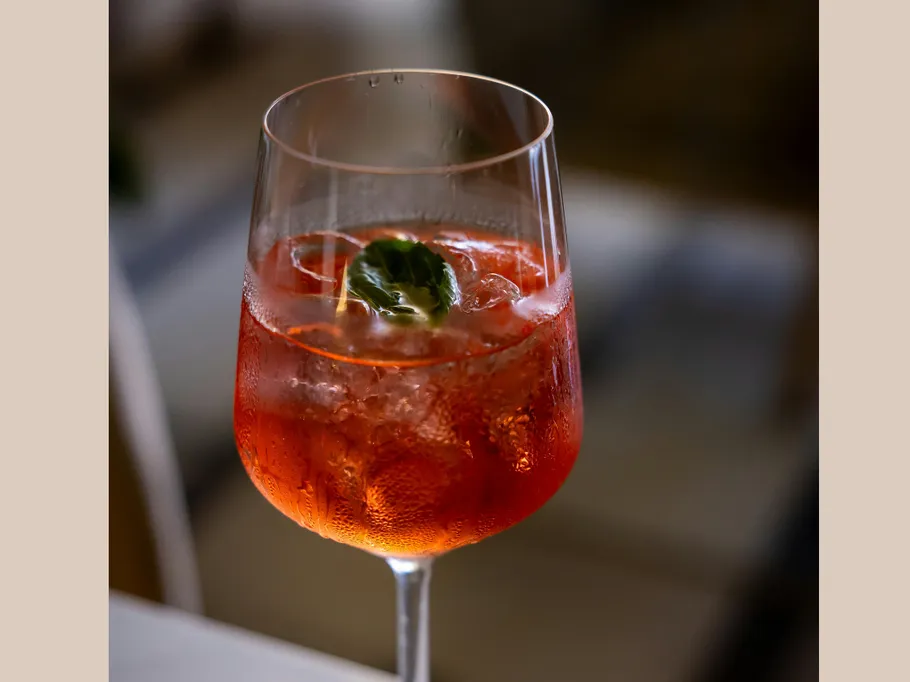 Roter Cocktail mit Basilikum im Glas.