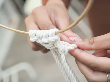 Hands tie rope around a nearby golden ring.