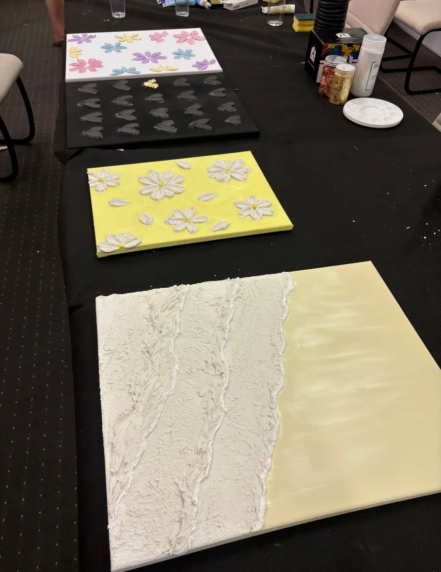 Three textured canvases on a black table.