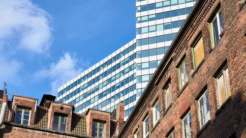 Moderner Wolkenkratzer hinter altem Backsteingebäude.