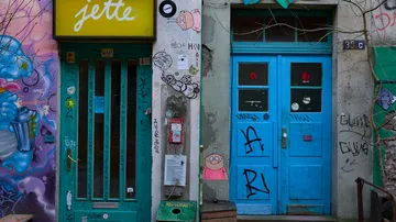 Colorful graffiti-covered building with blue doors.