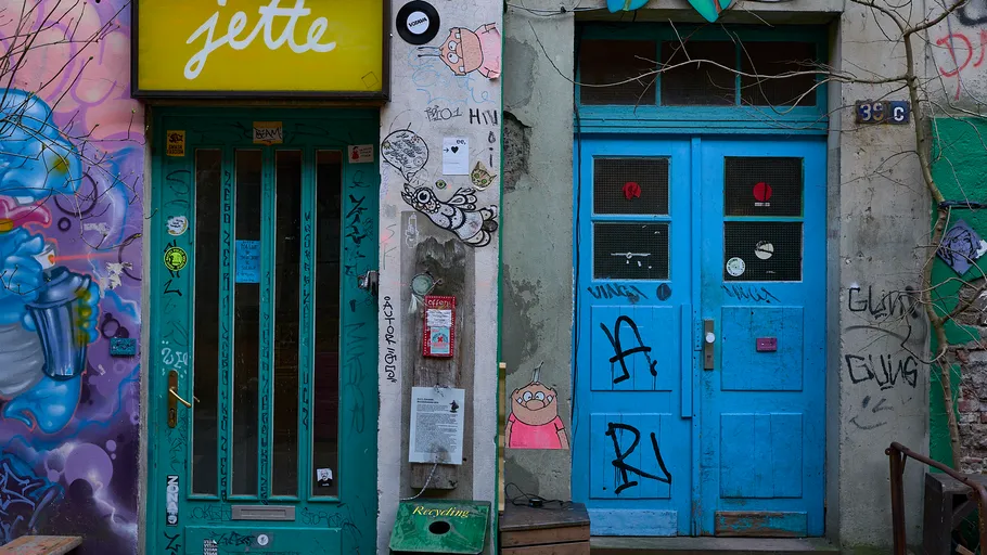 Colorful graffiti-covered building with blue doors.