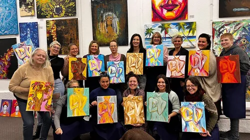 Group holding abstract paintings in an art gallery.
