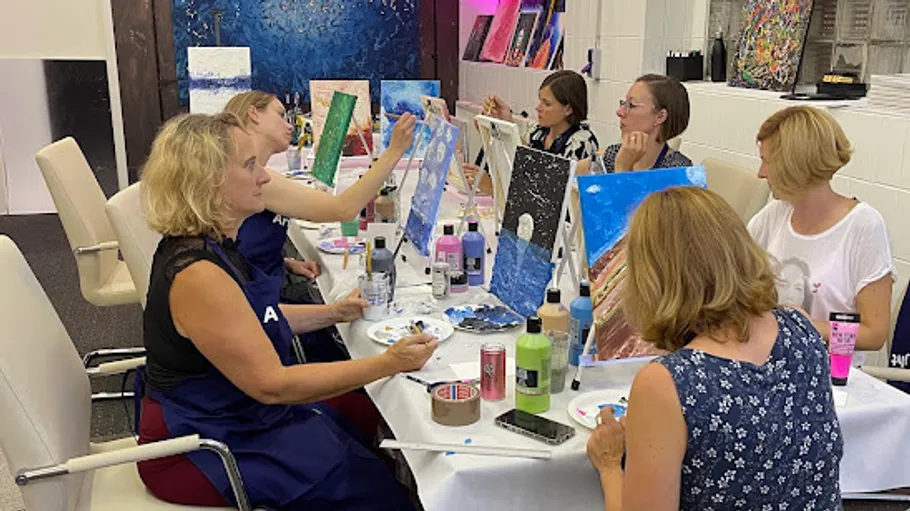 Women painting on canvases in a studio.