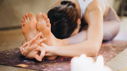 Person praktiziert Yoga auf einer Matte drinnen.