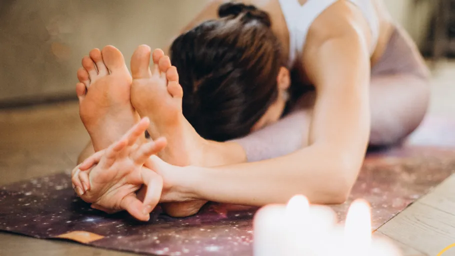 Person praktiziert Yoga auf einer Matte drinnen.