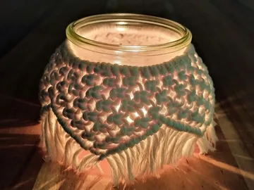 Glas mit einer gehäkelten Hülle, leuchtet sanft im Dunkeln.