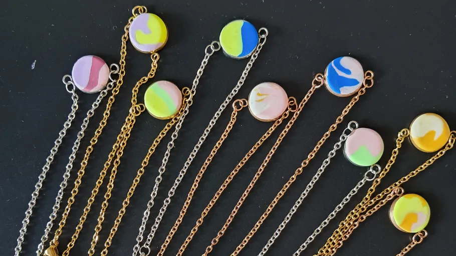 Bunte Anhänger an Ketten auf schwarzem Hintergrund.