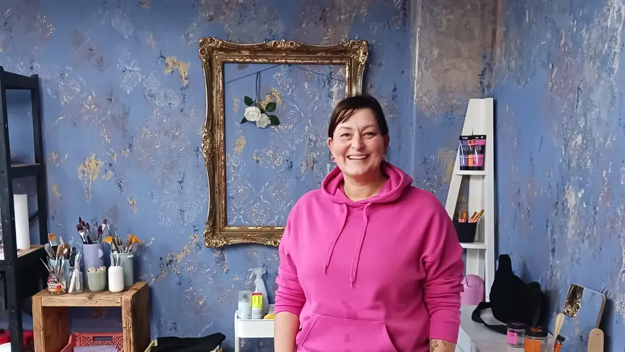 Lächelnde Frau im pinken Hoodie im Atelier.