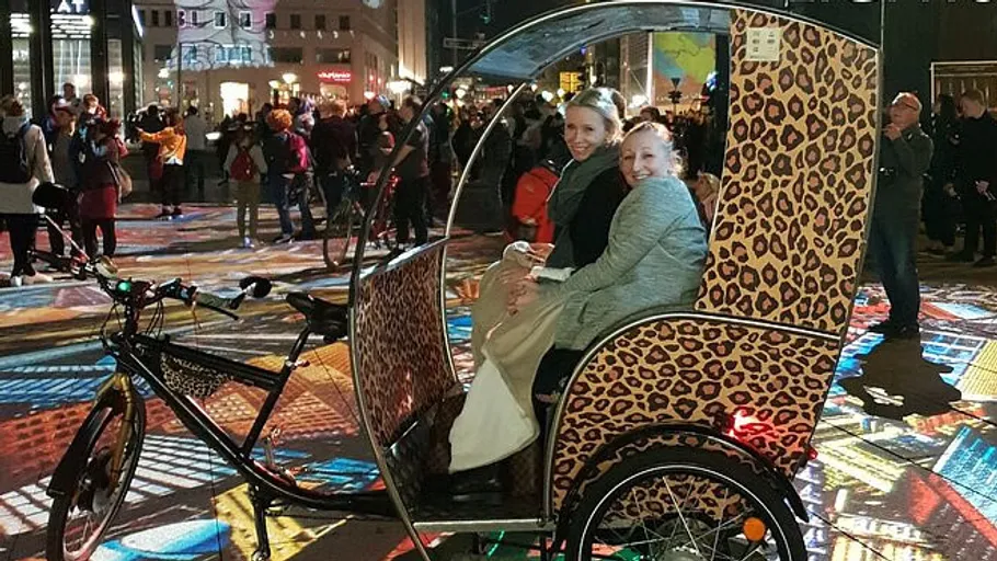 Zwei Frauen sitzen in einem Leopardenmuster-Rikscha.