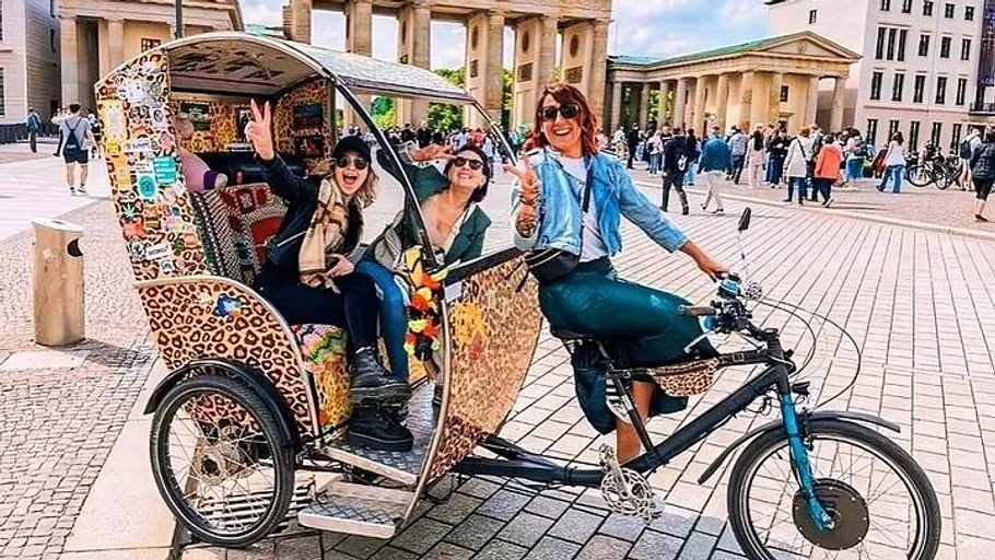 Menschen auf dekorierter Rikscha am Brandenburger Tor.