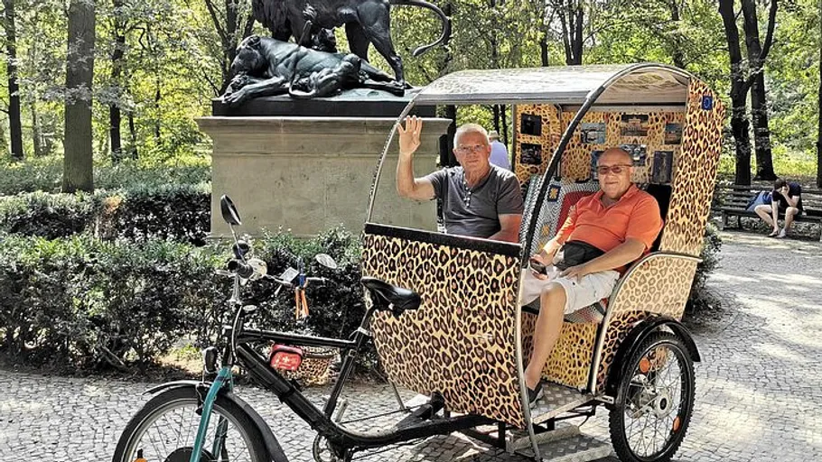 Two men in rickshaw near statue in park.