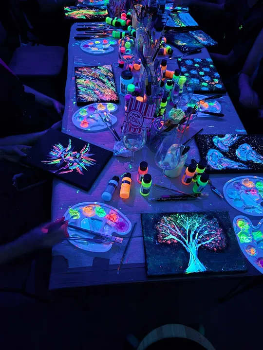 Glowing art supplies and paintings on table.