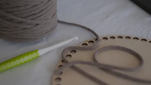 Crochet hook and yarn on a wooden board.